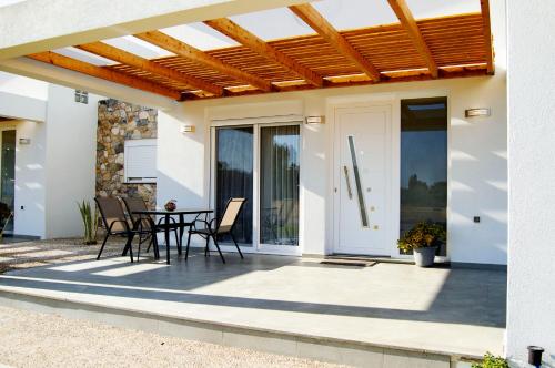 a patio with a table and chairs and a wooden pergola at Anna Maria's Maisonette I in Kardamaina