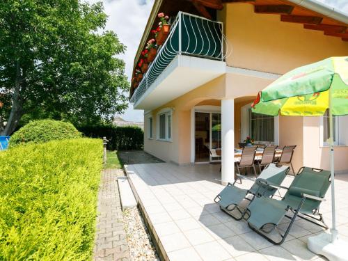 a patio with chairs and an umbrella next to a house at Holiday Home Pentaller by Interhome in Balatonföldvár