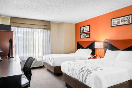 two beds in a hotel room with orange walls at Sleep Inn Billings in Billings