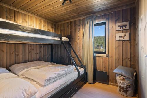 a bunk bed in a wooden room with a window at Ny eksklusiv hytte, strøm og jacuzzi inkl i prisen in Flå