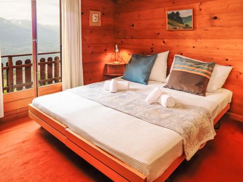 a bedroom with a large bed with a balcony at Chalet Mungg by Interhome in Nendaz