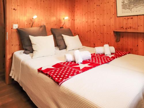 a bed with a red and white blanket on it at Chalet La Bergerie by Interhome in Nendaz