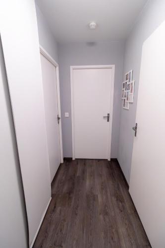 un couloir vide avec des portes blanches et du parquet dans l'établissement Appartement cosy et lumineux 2 pieces 10 mn de gare de Lyon, à Alfortville