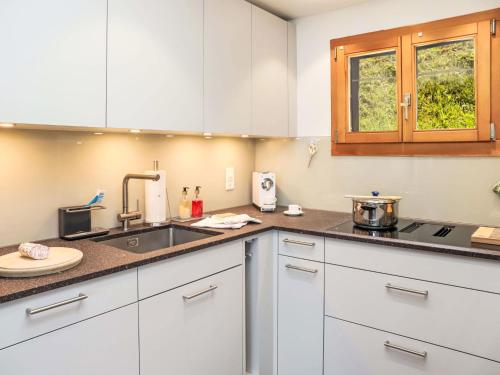 une cuisine avec des armoires blanches et un évier dans l'établissement Chalet Dorine by Interhome, à Nendaz