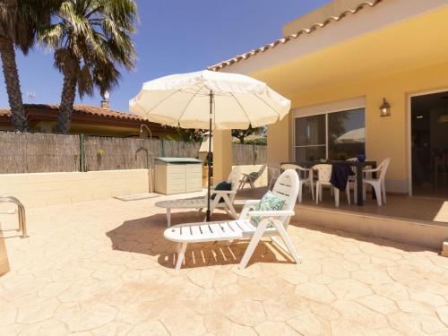 zwei Stühle und ein Sonnenschirm auf einer Terrasse in der Unterkunft Holiday Home Flamenc 3 by Interhome in Riumar