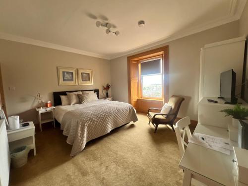 a bedroom with a bed and a chair and a window at Morven Guest House Carnoustie in Carnoustie