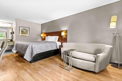 a bedroom with a bed and a couch and a chair at Rodeway Inn in Lexington
