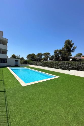 - une piscine avec de l'herbe verte à côté d'un bâtiment dans l'établissement Studio Résidence Le Boréal-2 by Interhome, à Saint-Raphaël
