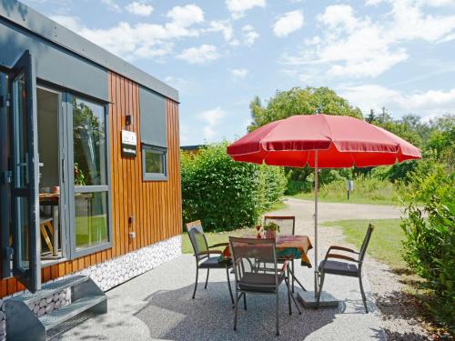 バイルングリースにあるHoliday Home Tiny Haus Hirschberg by Interhomeの赤い傘付きのテーブルのあるパティオ