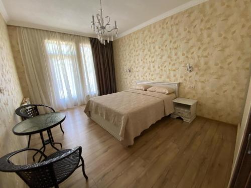 a bedroom with a bed and a table and chairs at Grand Villa Sadgeri in Borjomi