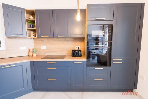 a kitchen with blue cabinets and a refrigerator at The Gozo Holiday Apartment that Feels like Home in Żebbuġ