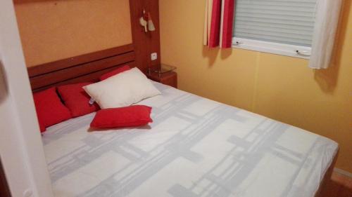 une chambre avec un lit blanc avec des oreillers rouges dans l'établissement les cigales, à Bauduen