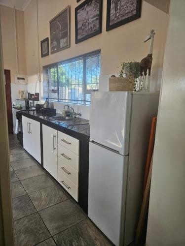 a kitchen with a white refrigerator and a sink at Hillton Manor Guest House in Richards Bay