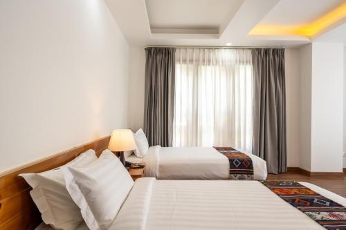 a hotel room with two beds and a window at Naksel Urban Hotel & Spa in Thimphu