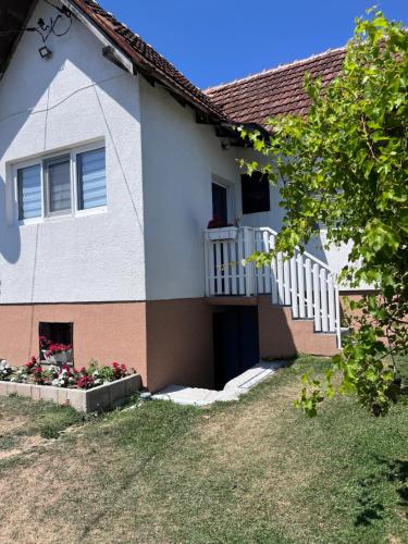 a house with a balcony and flowers in a yard at Dedina kuća in Gornji Milanovac