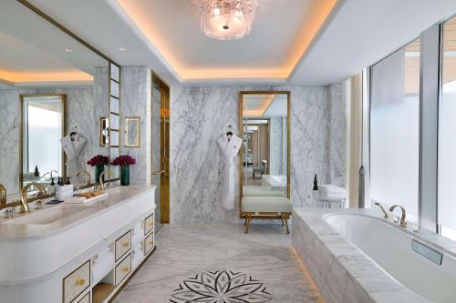 a bathroom with two sinks and a tub and a mirror at Waldorf Astoria Doha Lusail in Doha
