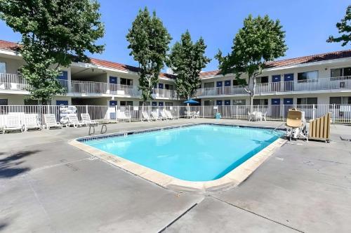 a swimming pool in front of a building with chairs at Park Inn by Radisson, San Jose in San Jose