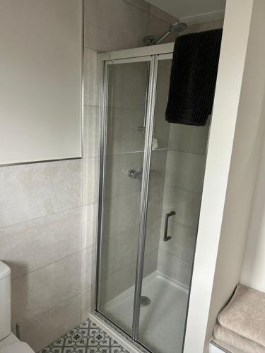a shower with a glass door in a bathroom at Stylish room for Cheltenham races in Woolstone