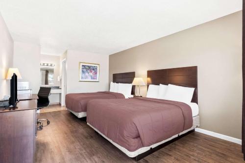 a hotel room with two beds and a flat screen tv at Rodeway Inn Hermiston - Umatilla in Hermiston