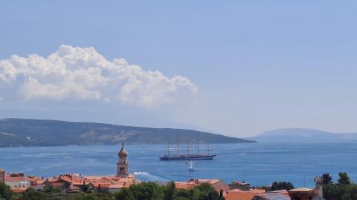 een boot die in het water drijft in de buurt van een stad bij Studio Apartments Maslinik in Krk