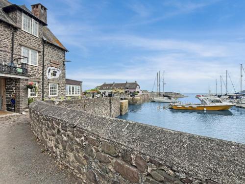 a stone wall next to a harbor with boats in the water at Harbour House Studio, Porlock Weir in Culbone