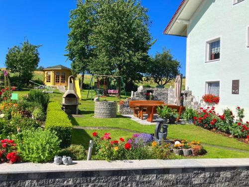 a garden in front of a house with flowers at Ferienwohnung Haus Elfriede in Neukirchen beim Heiligen Blut