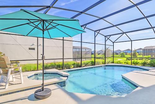 a pool with an umbrella and a chair and a table at Upstay Luxury Resort Home w Private Pool & Hot Tub in Kissimmee
