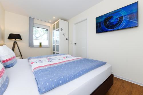 a bedroom with a bed and a television on the wall at Ferienwohnungen MARENOR in Bensersiel