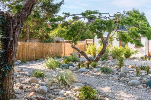 a garden with rocks and a tree and a fence at L'Atelier de l'Artiste - Lumineux - Calme - Wifi in Douai