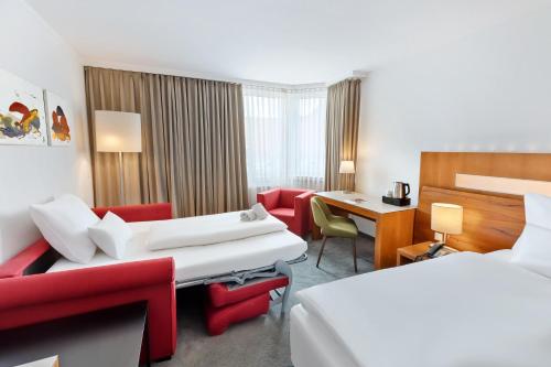 a hotel room with two beds and a desk at Austria Trend Hotel Europa Graz Hauptbahnhof in Graz