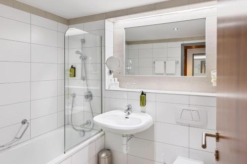 a white bathroom with a sink and a shower at Austria Trend Hotel Europa Graz Hauptbahnhof in Graz