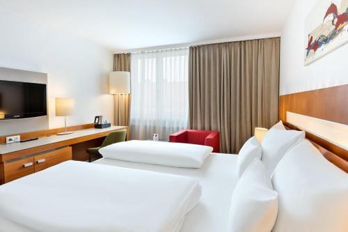 a hotel room with two beds and a desk at Austria Trend Hotel Europa Graz Hauptbahnhof in Graz
