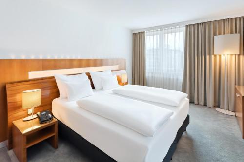 a hotel room with a large bed with white sheets at Austria Trend Hotel Europa Graz Hauptbahnhof in Graz