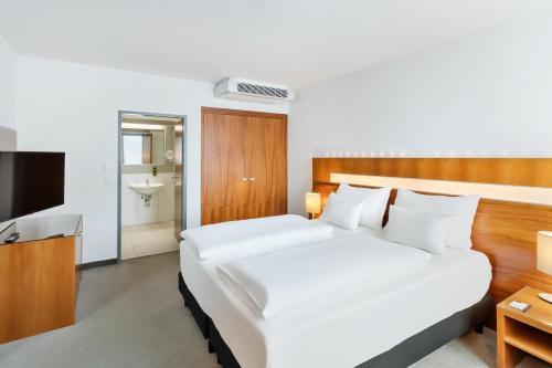 a bedroom with a large white bed and a television at Austria Trend Hotel Europa Graz Hauptbahnhof in Graz