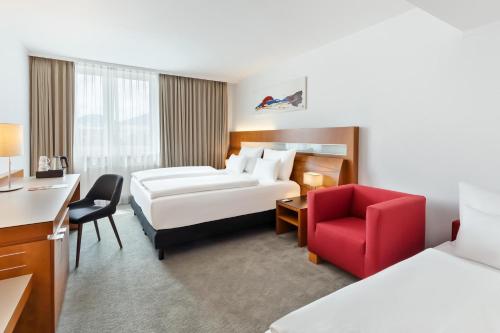 a hotel room with a bed and a red chair at Austria Trend Hotel Europa Graz Hauptbahnhof in Graz