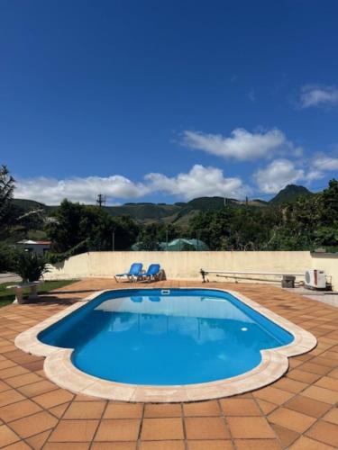 a large swimming pool with two blue chairs in it at Casa da Fazenda in Santa Cruz das Flores