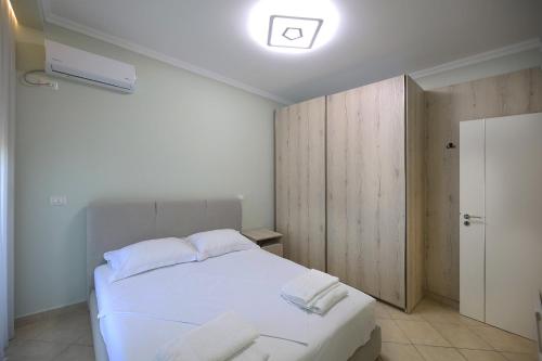 a bedroom with a white bed and a wooden cabinet at Holiday Apartment in Vlorë