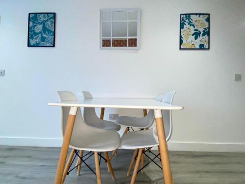 a white table and four white chairs in a room at Apartment 2 in Manchester