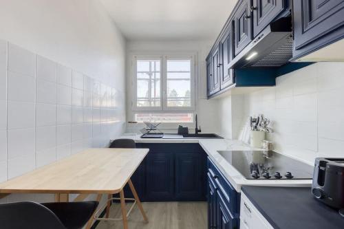 une cuisine avec des placards bleus et une table en bois dans l'établissement Votre pied-à-terre Parisien à Montreuil-Fontenay, à Montreuil