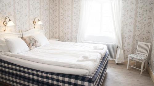 a white bed in a room with a window at Färna Herrgård & Spa in Färna