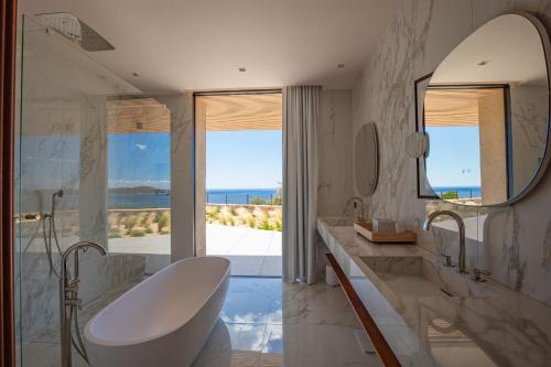 une salle de bain avec une baignoire, un lavabo et un miroir dans l'établissement Villa Lucia Arinella, à Pinarellu