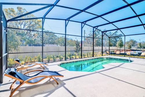 a swimming pool in a glass house with a patio furniture at 8BR Resort Home with Games Room and BBQ in Kissimmee