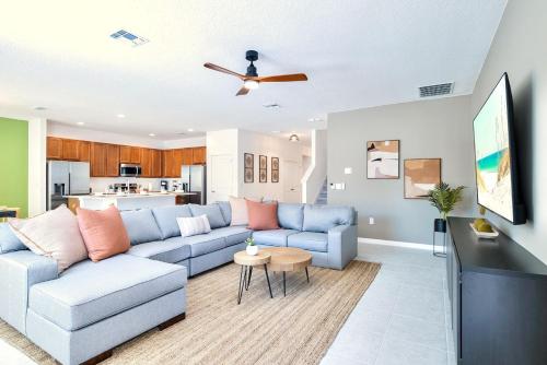 a living room with a blue couch and a kitchen at 8BR Resort Home with Games Room and BBQ in Kissimmee