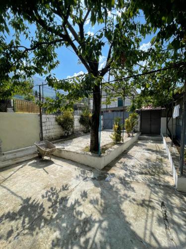 un árbol frente a un edificio con una valla en Peaceful Garden House, en Përmet