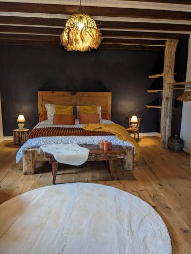 une chambre avec un grand lit et un lustre dans l'établissement La Fuly d'en haut, à Le Grand-Abergement