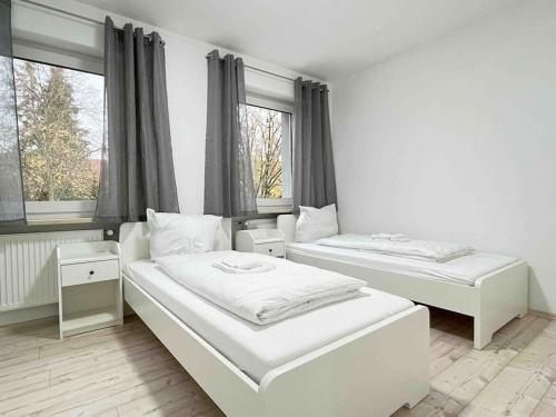 two beds in a room with two windows at LAP101 - Große Moderne Monteurwohnung Übergangswohnung in Lappersdorf