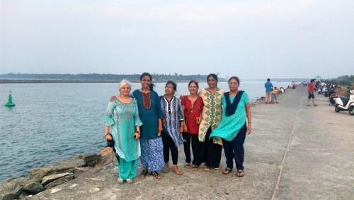 a group of women standing next to the water at kadalundi Heritage in Vallikunnu