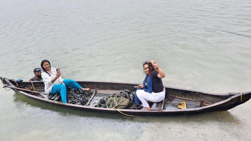 three women sitting in a boat in the water at kadalundi Heritage in Vallikunnu