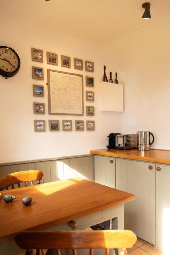 a kitchen with a table and a clock on the wall at Shepherd's Hut at High Gardens in Hereford
