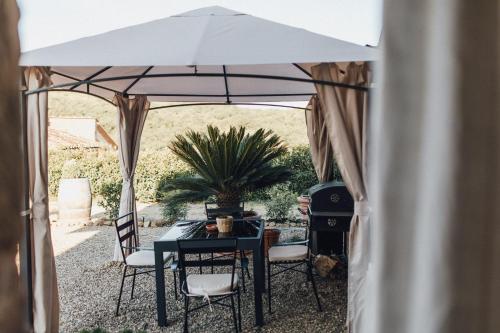 a table and chairs under a white umbrella at Podere Biricocolo - Il Cortile in Bucine
